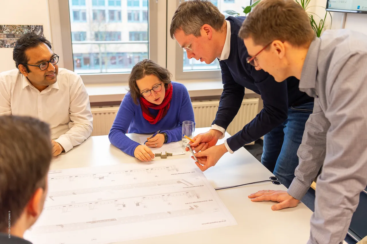 Planungsteam von DITTMANN+INGENIEURE bespricht Pläne am Tisch